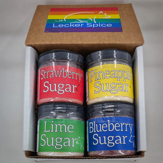 Four jars of flavored sugar in a box with Lecker Spice branding. Strawberry, Pineapple, Lime, and Blueberry Sugars